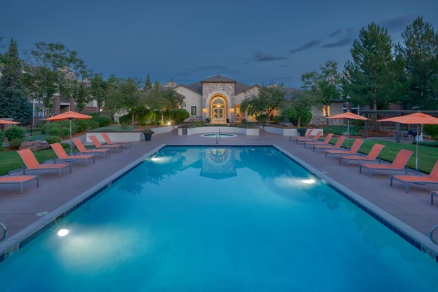 Pool area with lounge chairs at dusk at Legend Oaks Apartments in Aurora, Colorado